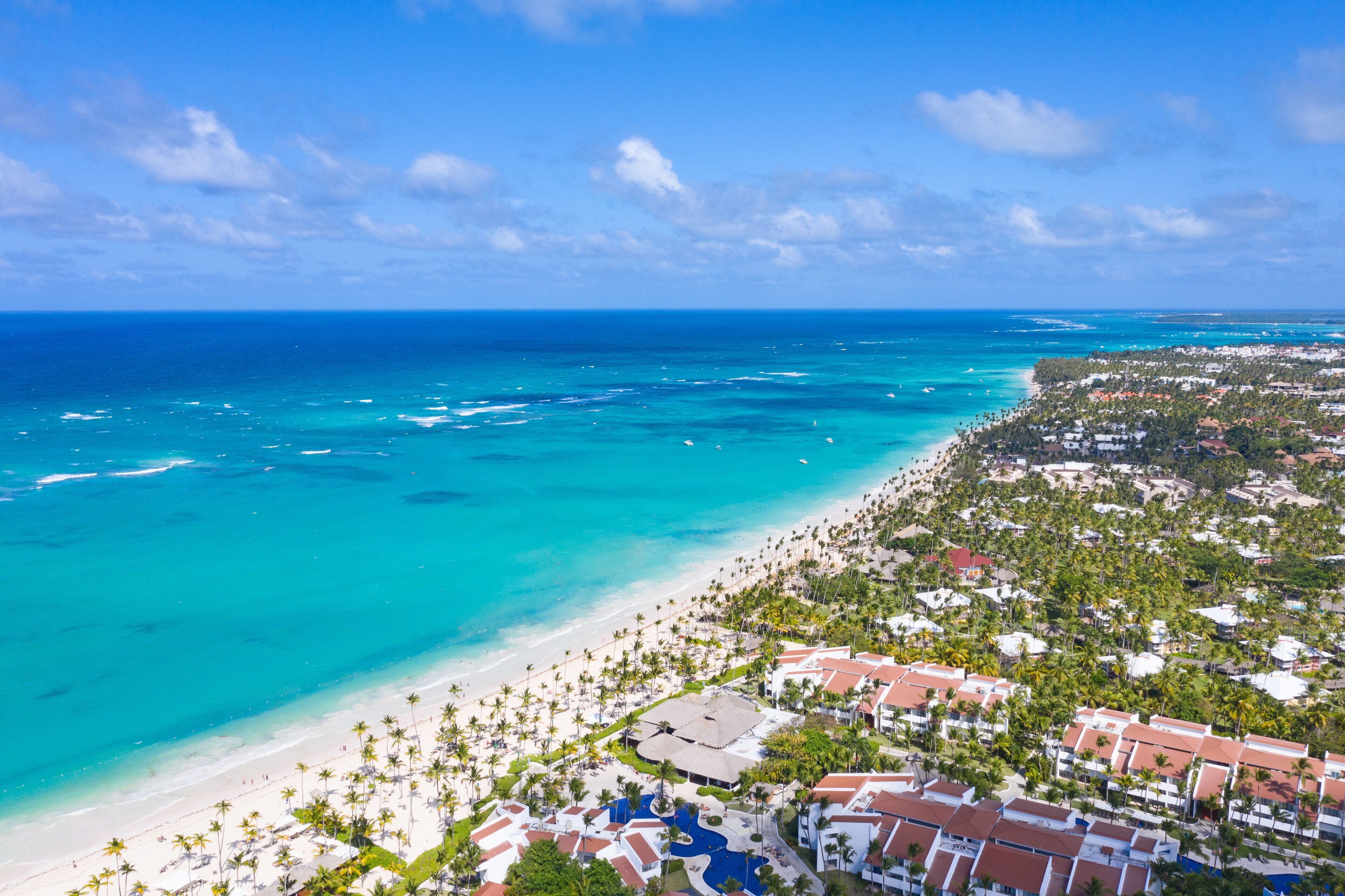 Vista aérea de playa Bávaro en Punta Cana, con arena blanca, palmeras y mar turquesa.