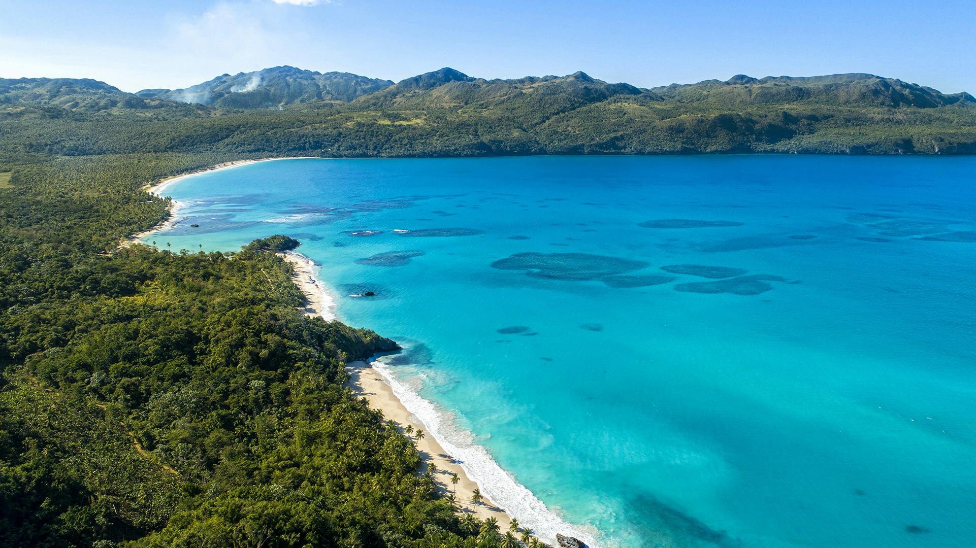 Playa Rincón en Samaná desde el aire, con costa verde, montañas y aguas turquesas.